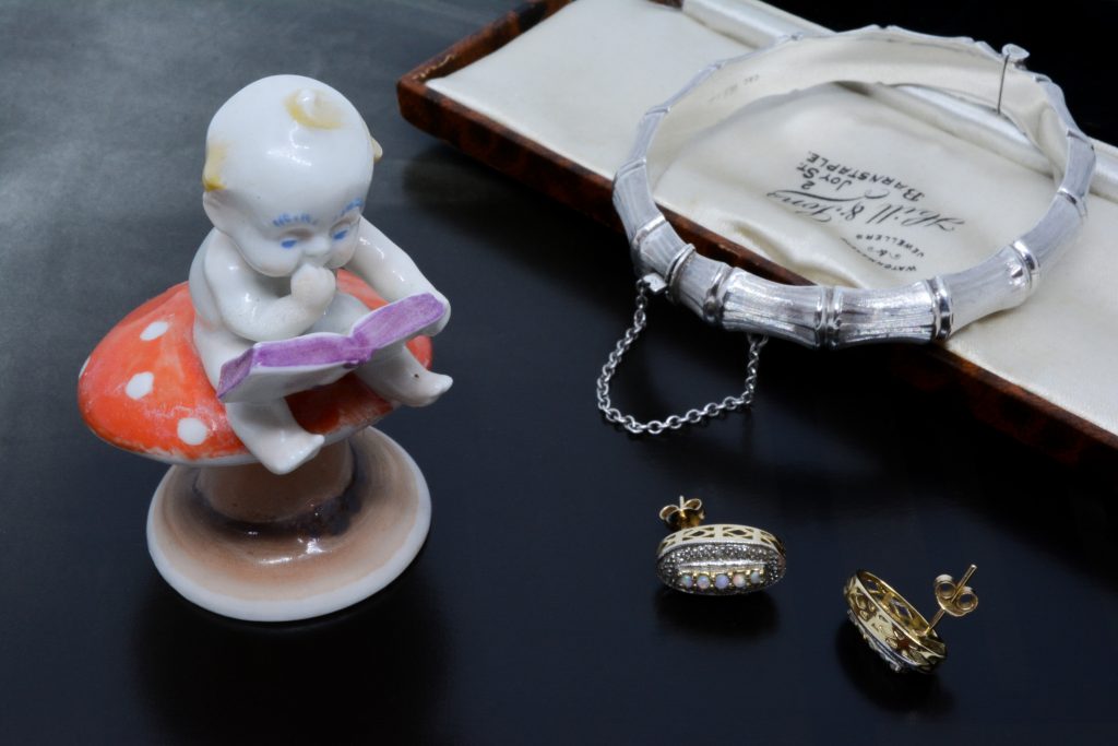 A collection of items including a cute porcelain figure reading on a toadstool.